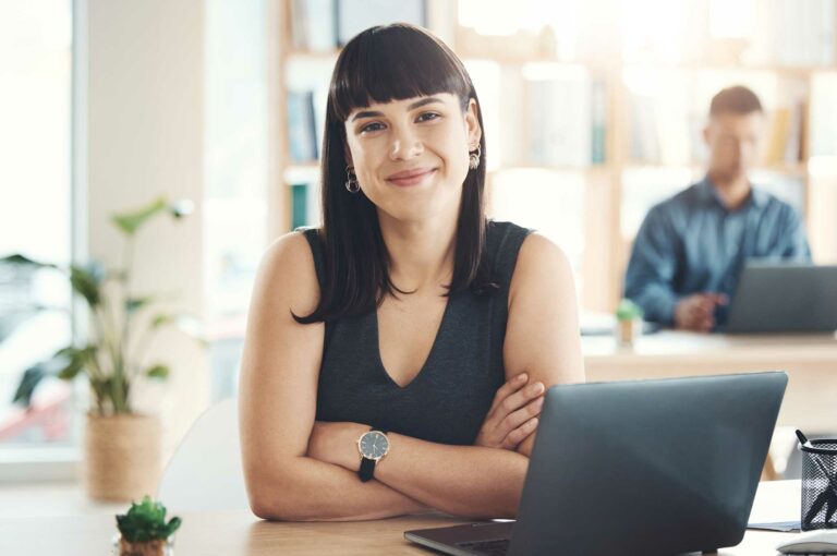 Woman with arms crossed sitting in front of a laptop