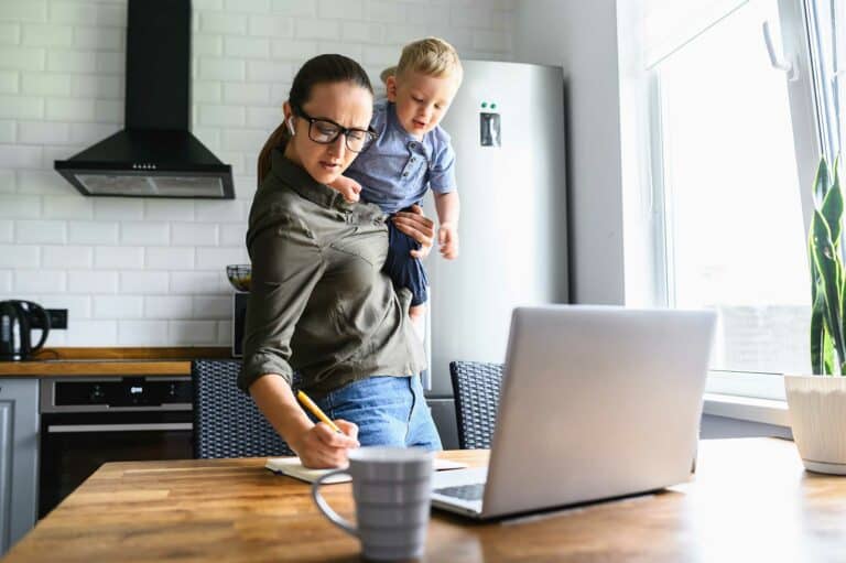 Woman holding a child while writing in a notebook