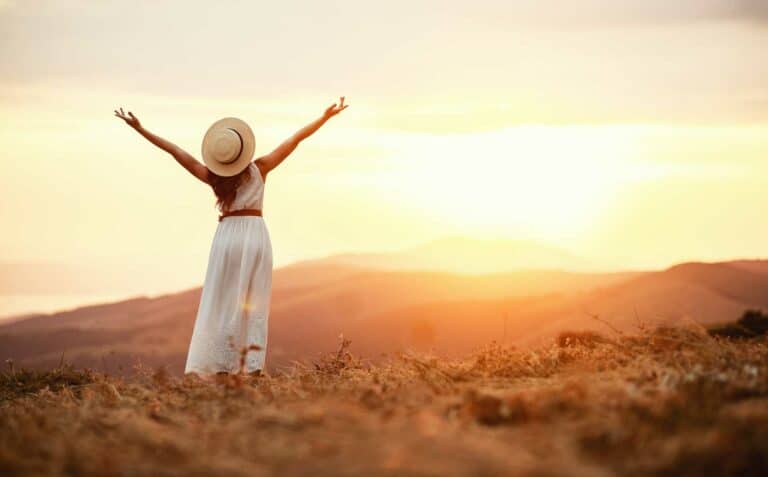 Woman standing in the hills with her arms up