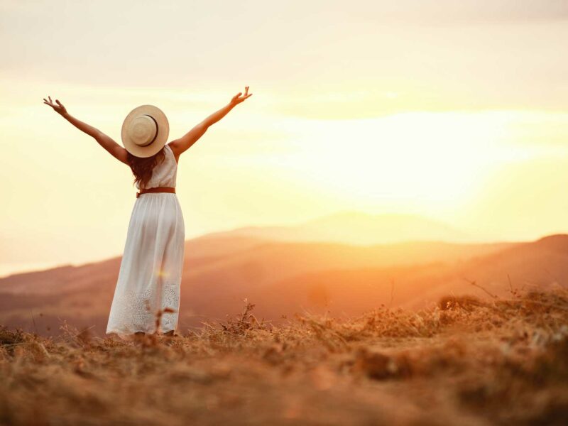 Woman standing in the hills with her arms up