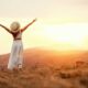 Woman standing in the hills with her arms up