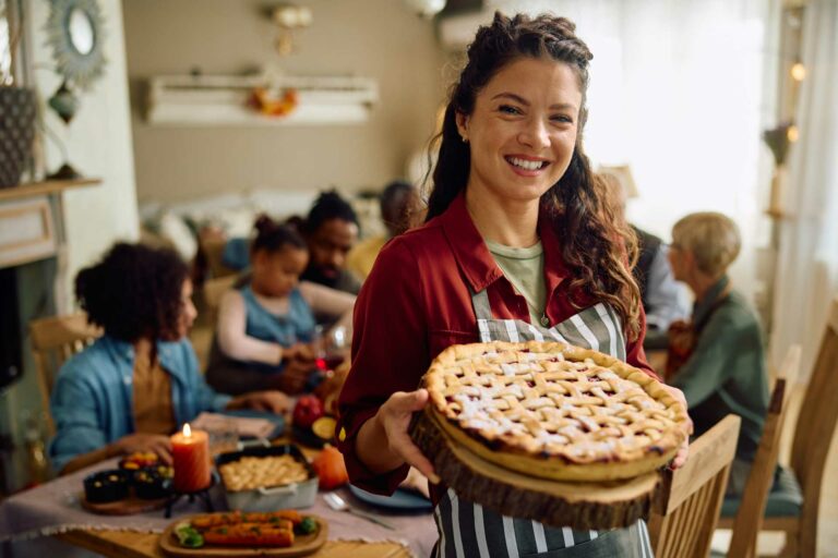 Woman holding a pie in front of a group of people at a table. Success is not pie! There's plenty to go around.