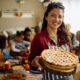 Woman holding a pie in front of a group of people at a table. Success is not pie! There's plenty to go around.