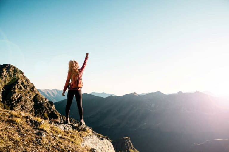 Woman standing on top of a mountain with her arm raised