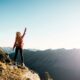 Woman standing on top of a mountain with her arm raised