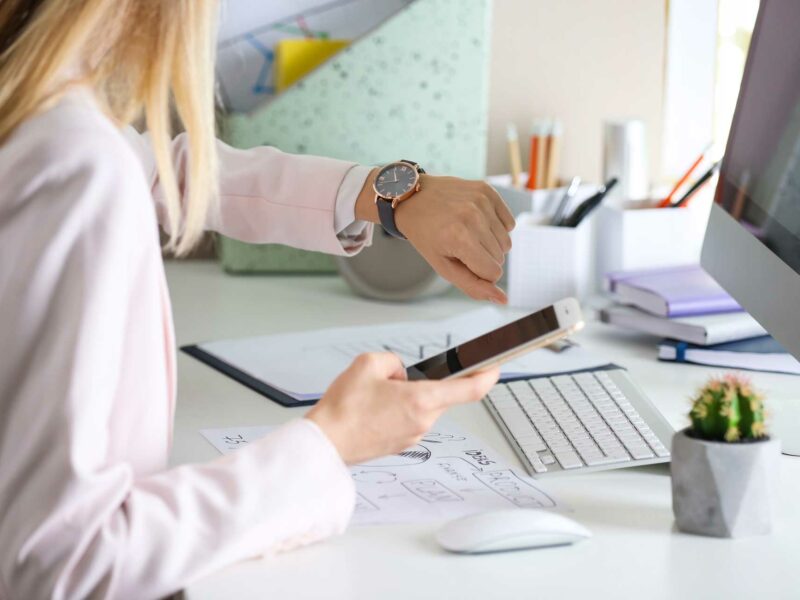 Woman looking at her watch while holding her phone