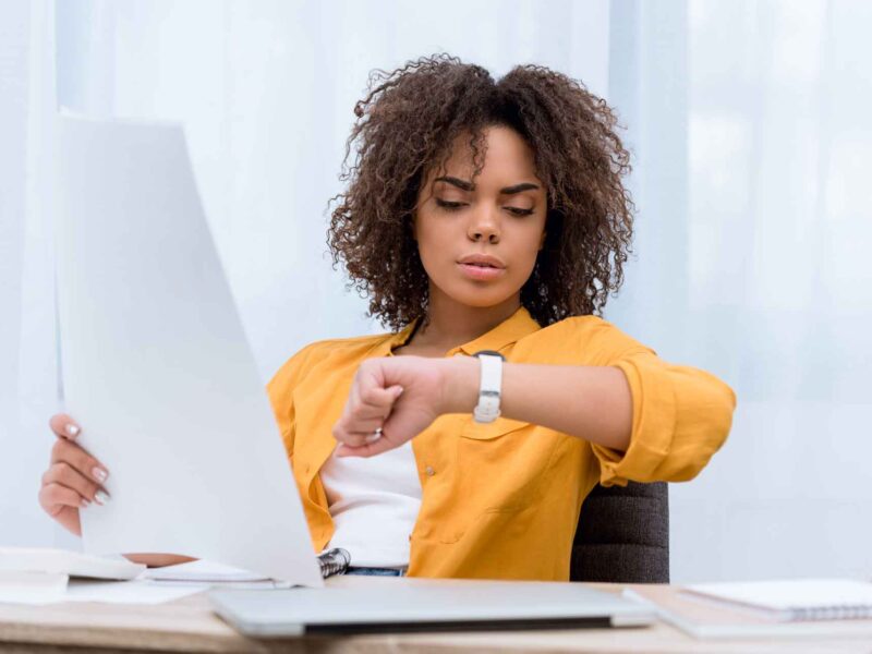 Woman looking at her watch as she implements time management techniques