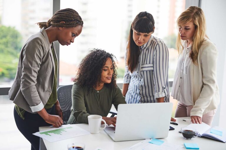 Group of women looking at a laptop to scope out their competition